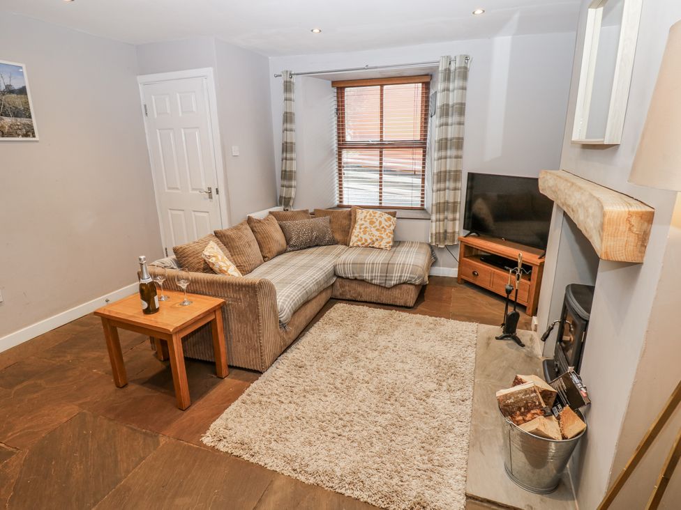A living room with a sofa, coffee table, and television at Mill Race House in Alston