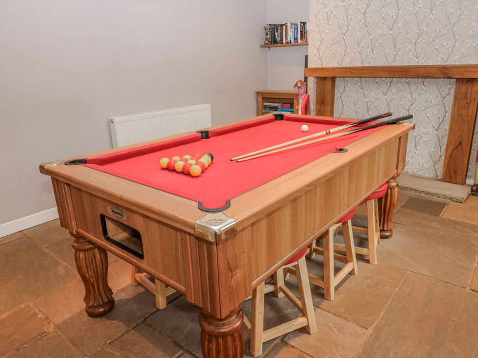 A game room with a pool table and cues at Mill Race House in Alston