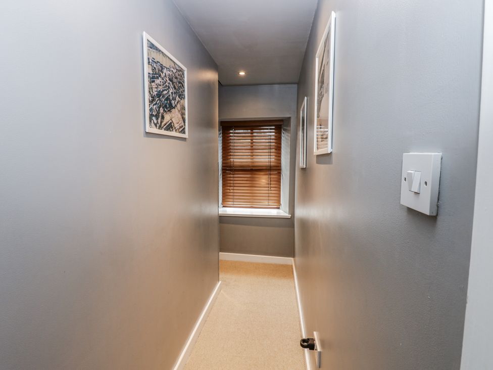 A hallway with framed pictures and a window at Mill Race House in Alston
