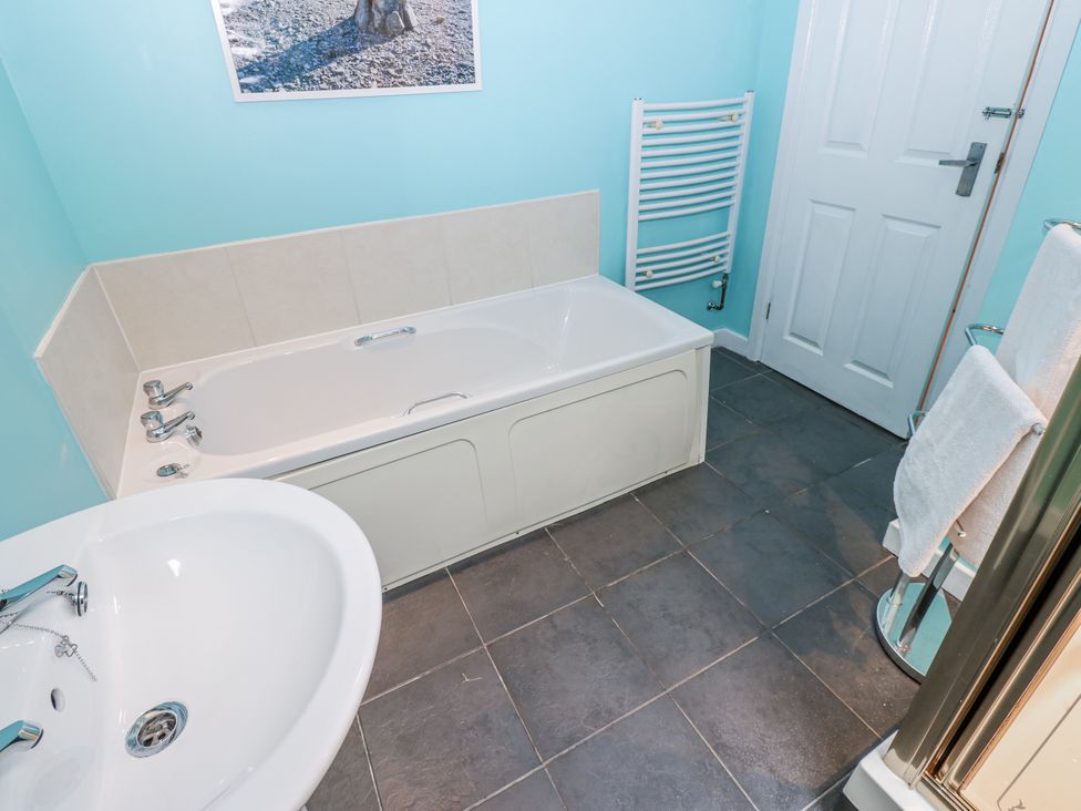 A bathroom with a bathtub and sink at Mill Race House in Alston