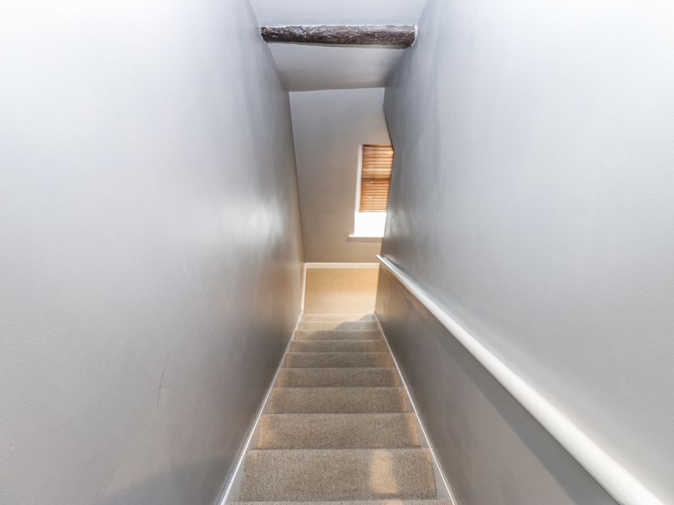 A staircase with a handrail and a window at Mill Race House Alston