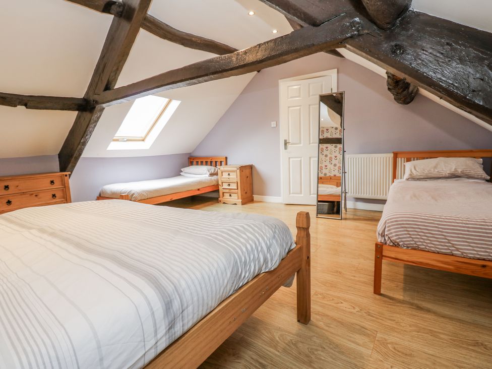 A bedroom with three beds and a mirror at Mill Race House in Alston