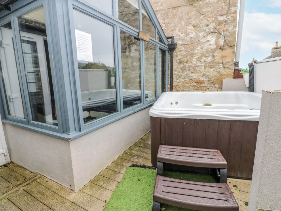 An outdoor area with a hot tub and decking at Mill Race House in Alston