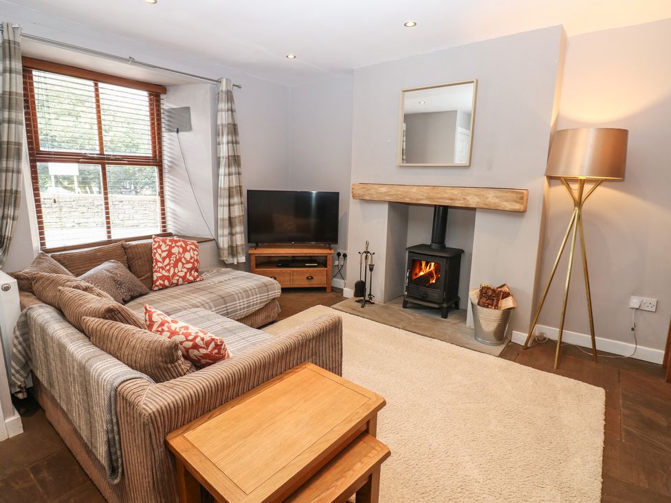 A living room with a sofa, television, and fireplace at Mill Race House in Alston