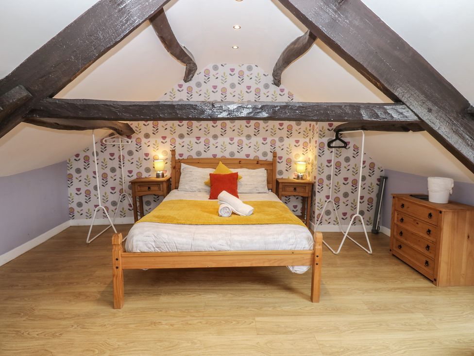 An attic bedroom with a bed and dresser at Mill Race House in Alston