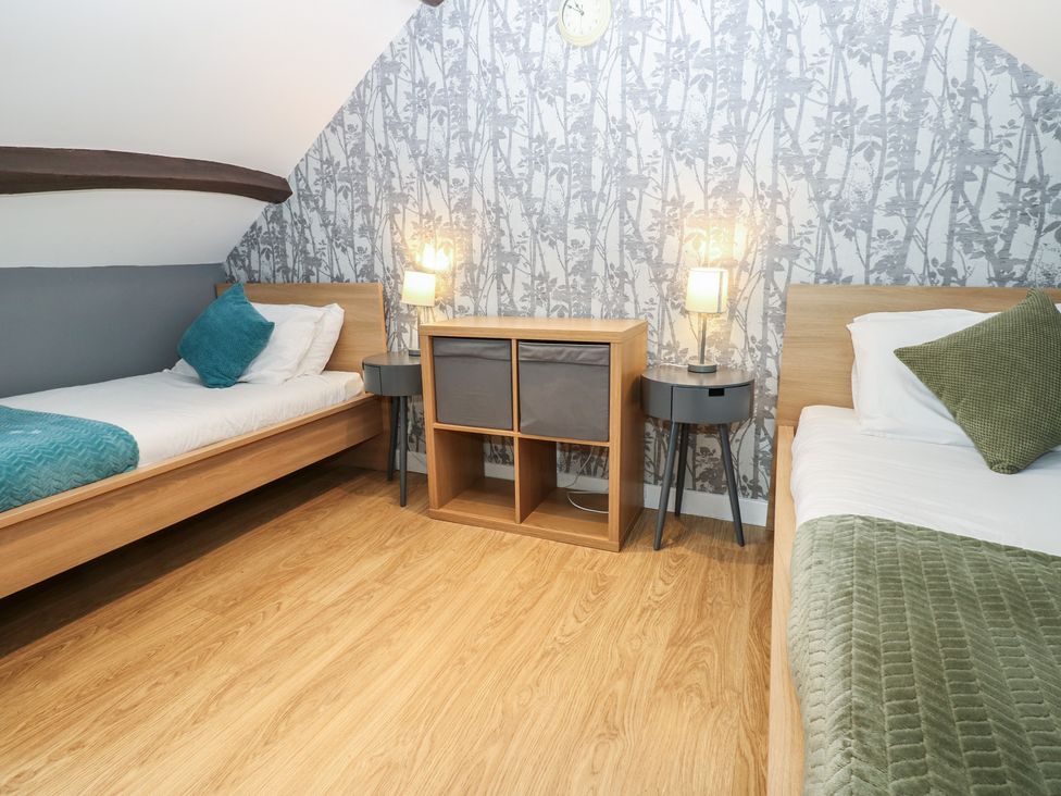 A bedroom with two beds and a storage unit at Mill Race House Alston