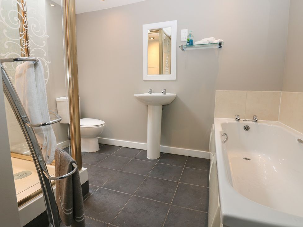 A bathroom with a bath tub, shower, sink and toilet at Mill Race House in Alston