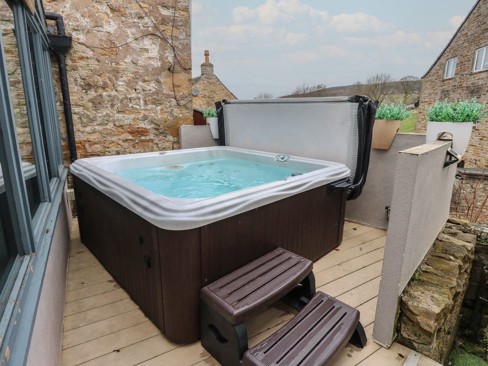 An outdoor area with a hot tub on a wooden deck at Mill Race House Alston