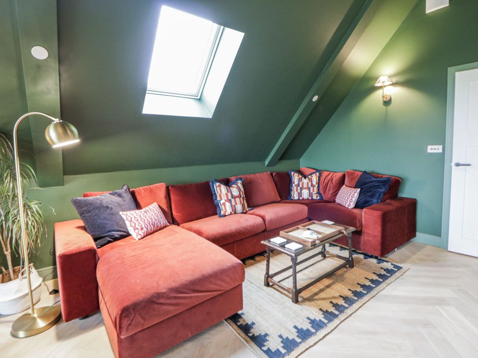 A living room with a red sofa and a coffee table at Twyn Isaf in Borth