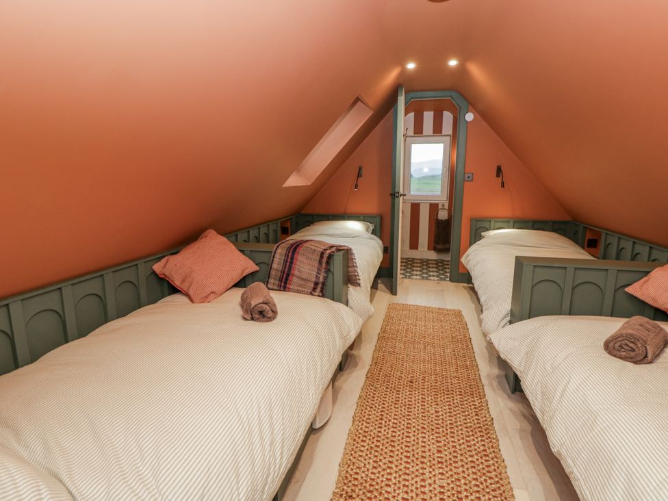 A bedroom with two beds and a door leading outside at Twyn Isaf Borth