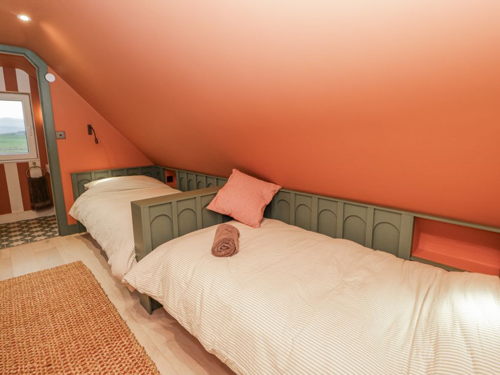 A bedroom with two single beds and a window at Twyn Isaf in Borth