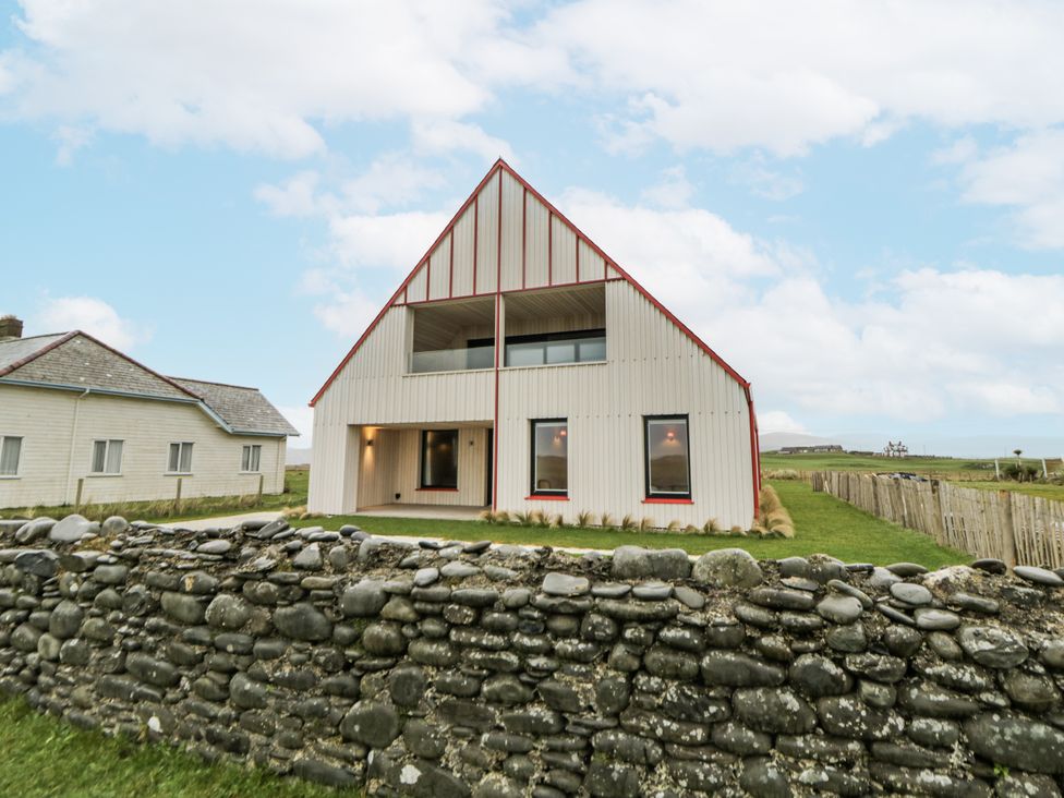 An exterior view of a house with a stone wall at Twyn Isaf in Borth