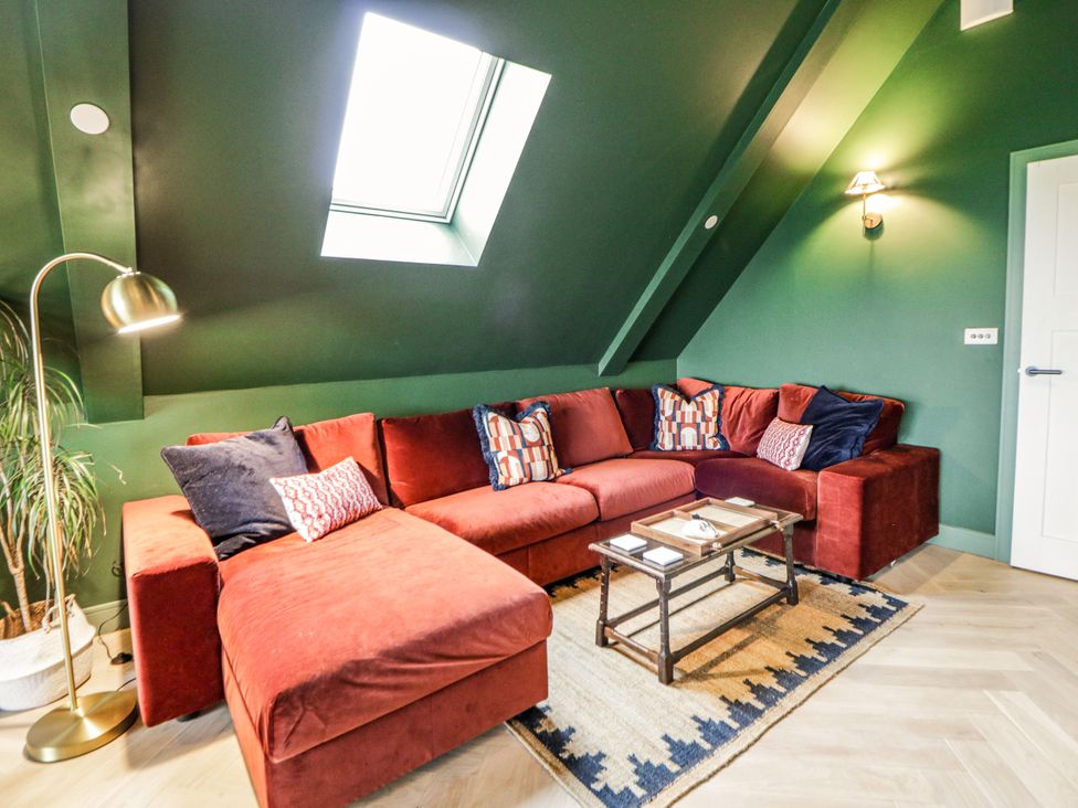 A snug with a red sectional sofa and a coffee table at Twyn Isaf in Borth