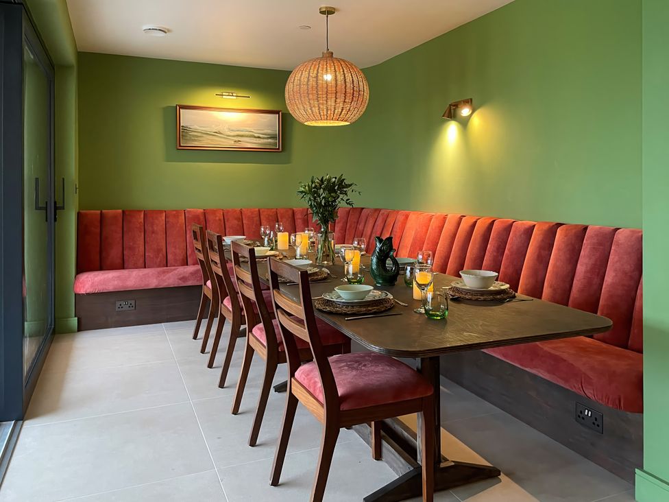 A dining room featuring a long table with chairs and a bench at Twyn Isaf in Borth
