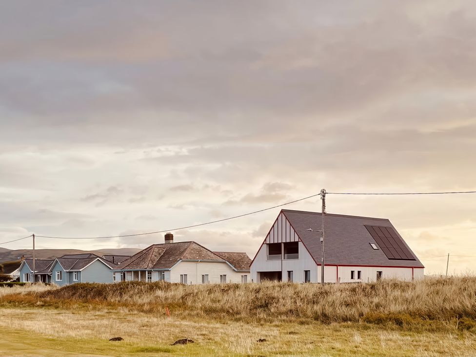 A row of houses with a cloudy sky at Twyn Isaf in Borth