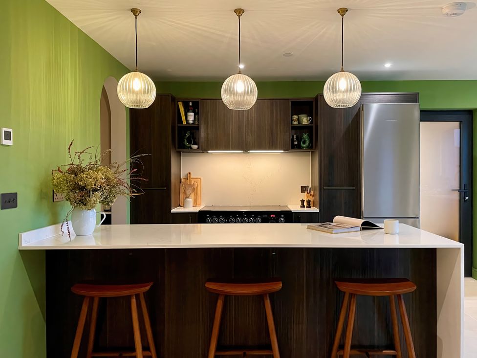 A kitchen with a modern design and bar stools at Twyn Isaf in Borth