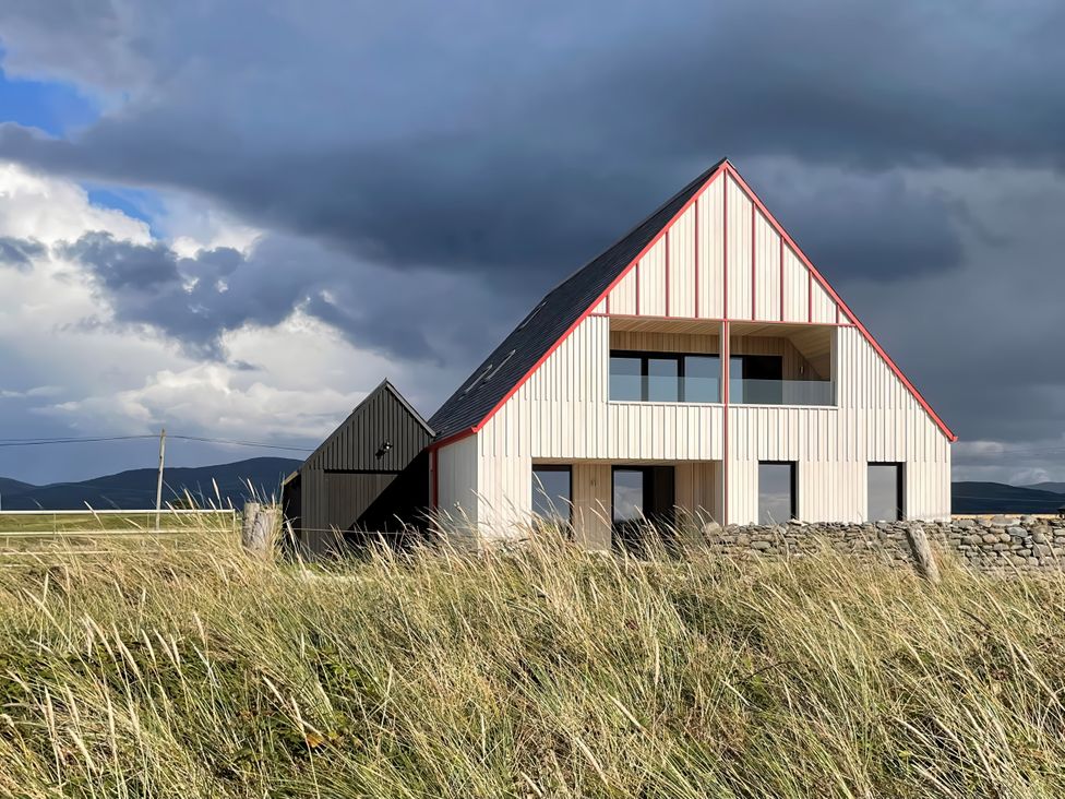 A house with windows and a roof in front of a grassy area at Twyn Isaf in Borth