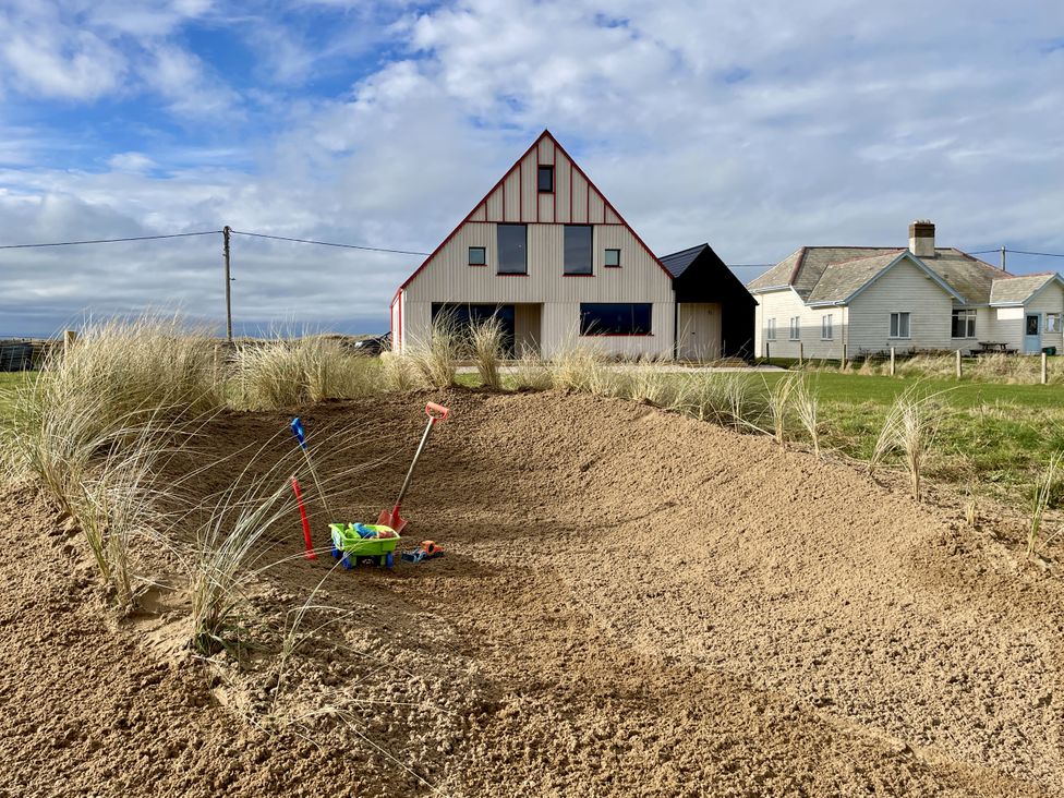 An outdoor area with sand and a house at Twyn Isaf in Borth