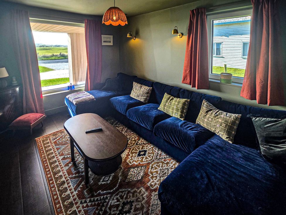 A living room with a blue sofa and a coffee table at Twyn Isaf in Borth