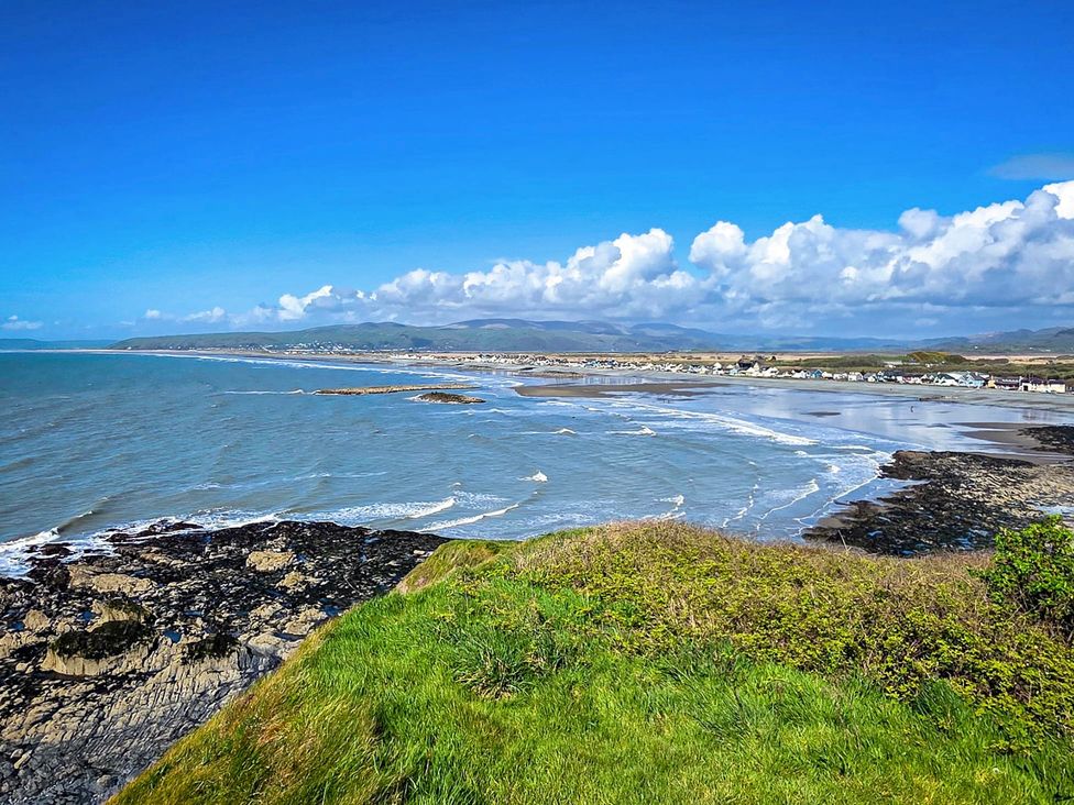 A coastal view showing ocean, beach, and rocks at Twyn Isaf in Borth