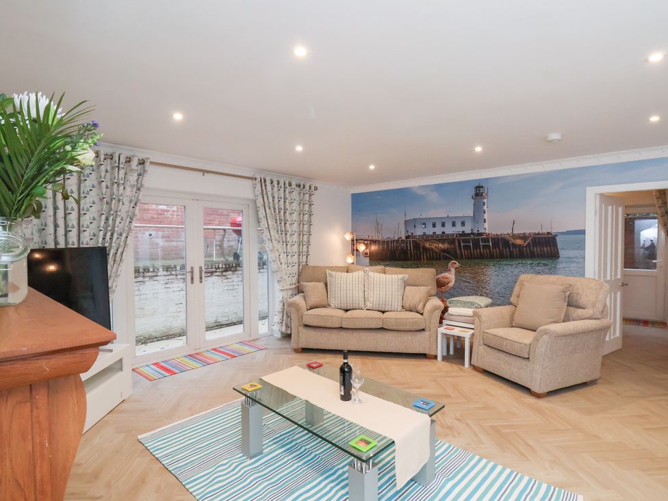 A living room with sofas, a coffee table, and doors leading outside at 32 Quay Street Scarborough