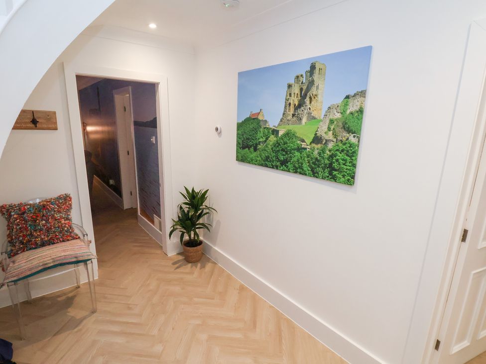 A hallway featuring a chair with a cushion and wall art at 32 Quay Street Scarborough