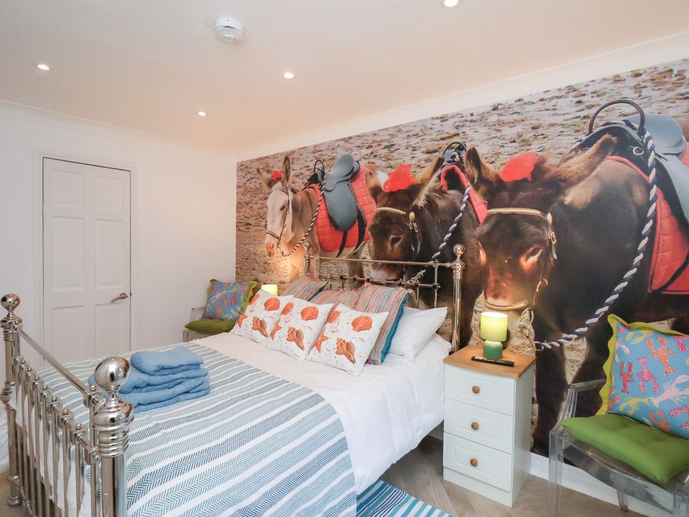 A bedroom with a bed, bedside table, and wall mural at 32 Quay Street Scarborough
