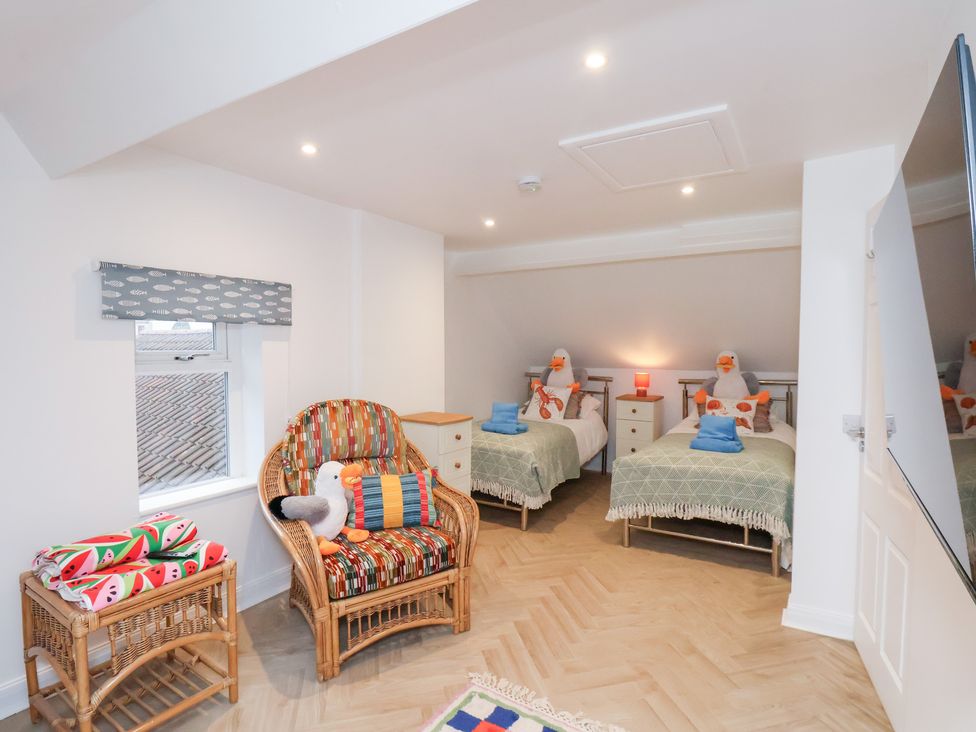 A bedroom with two beds and a rattan chair at 32 Quay Street Scarborough