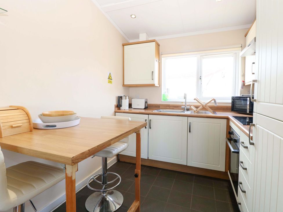 A kitchen with a table and stools at Boa Vista in Bacton