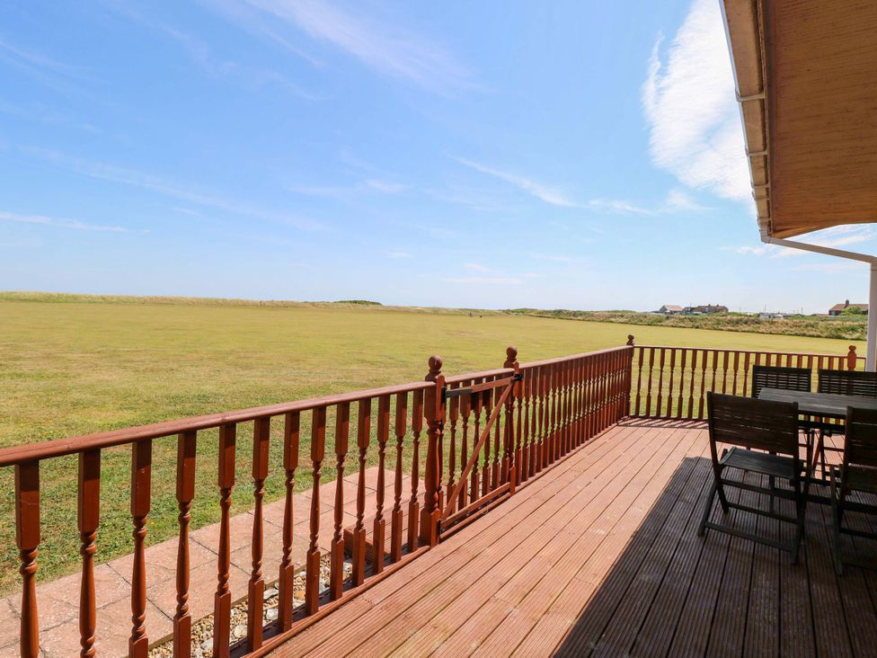 An outdoor area with a table and chairs on decking at Boa Vista in Bacton