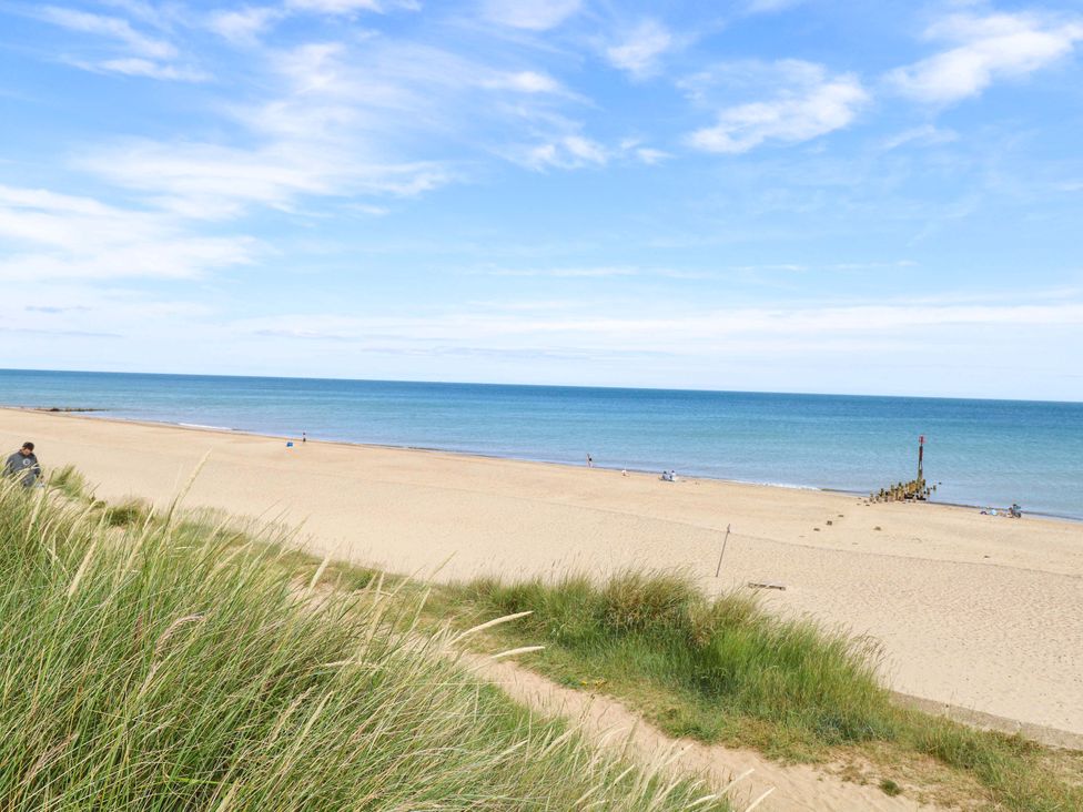 A beach with sand, grass, and water at Boa Vista in Bacton