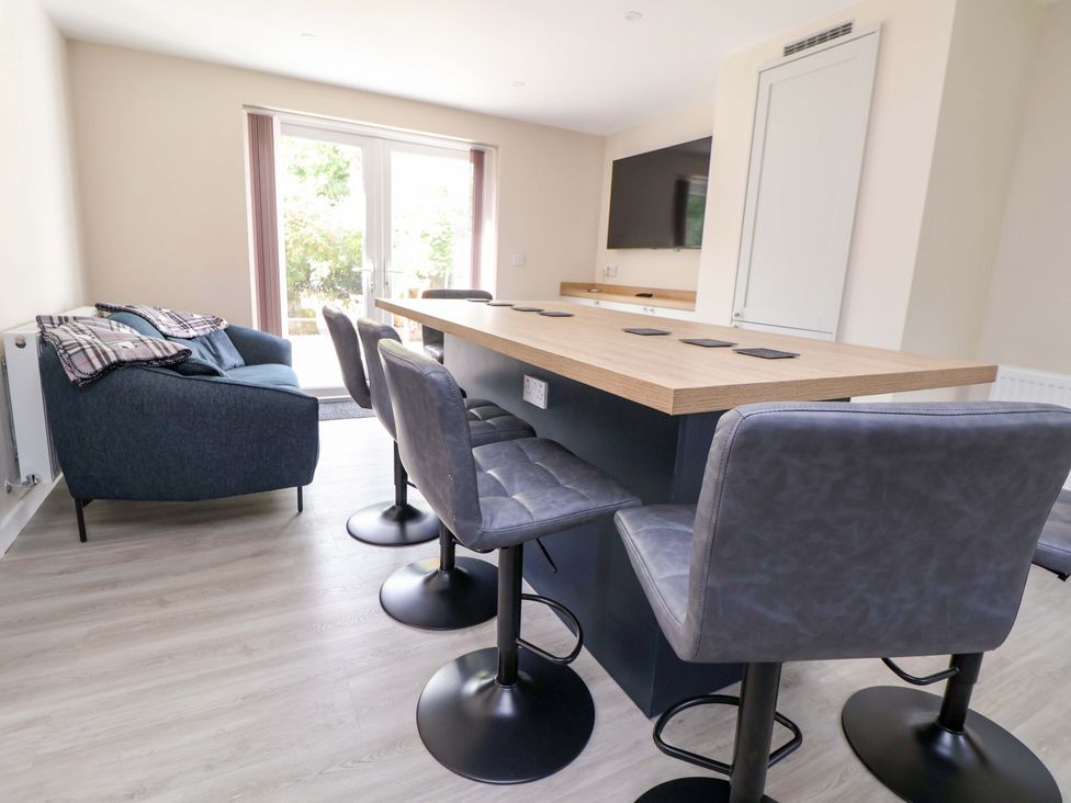 A dining room with a bar table and stools at Cartref Pen Y Ball near Holywell