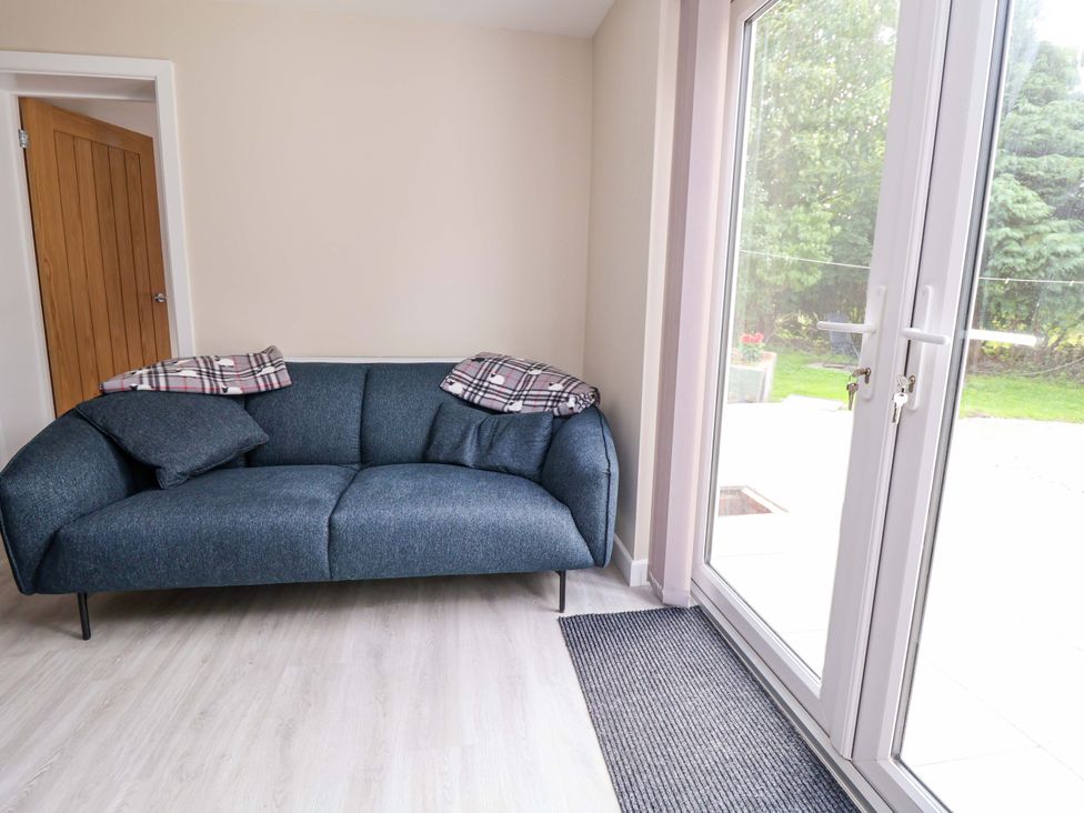 A snug with a sofa and a door at Cartref Pen Y Ball near Holywell