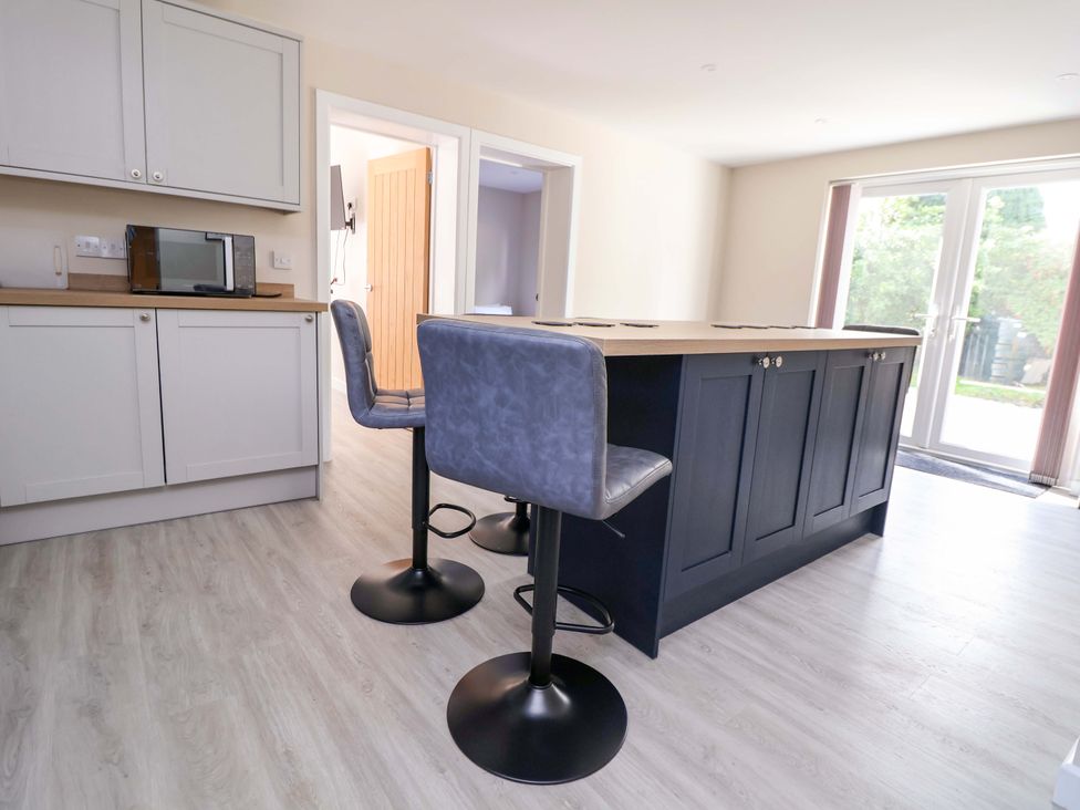 A kitchen with a bar island and stools at Cartref in Pen Y Ball near Holywell