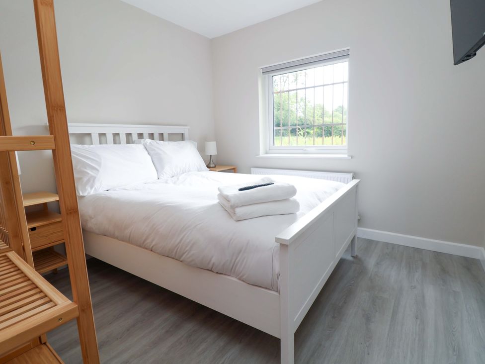 A bedroom with a bed and lamp at Cartref in Pen Y Ball near Holywell