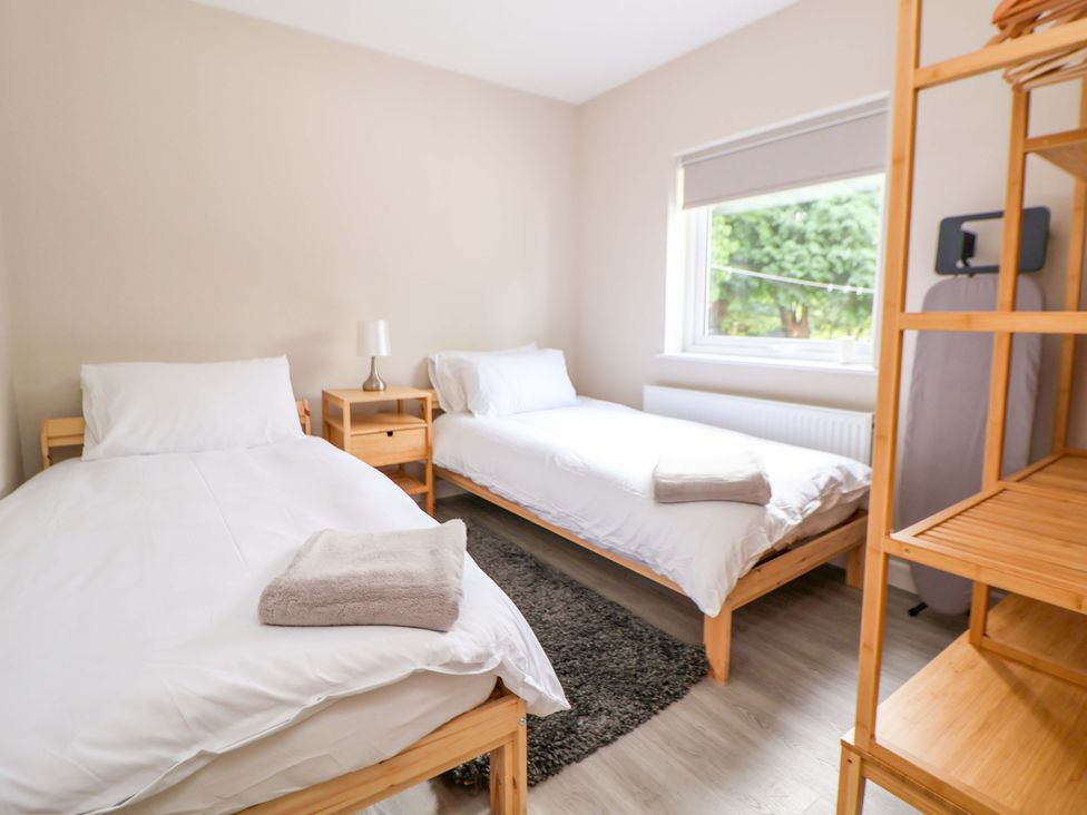 A bedroom with two single beds and a wooden shelf at Cartref Pen Y Ball near Holywell