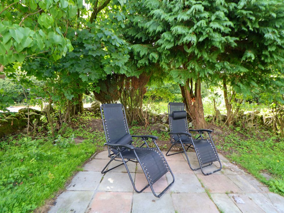 Two chairs on a stone patio under a tree at Cartref Pen Y Ball near Holywell