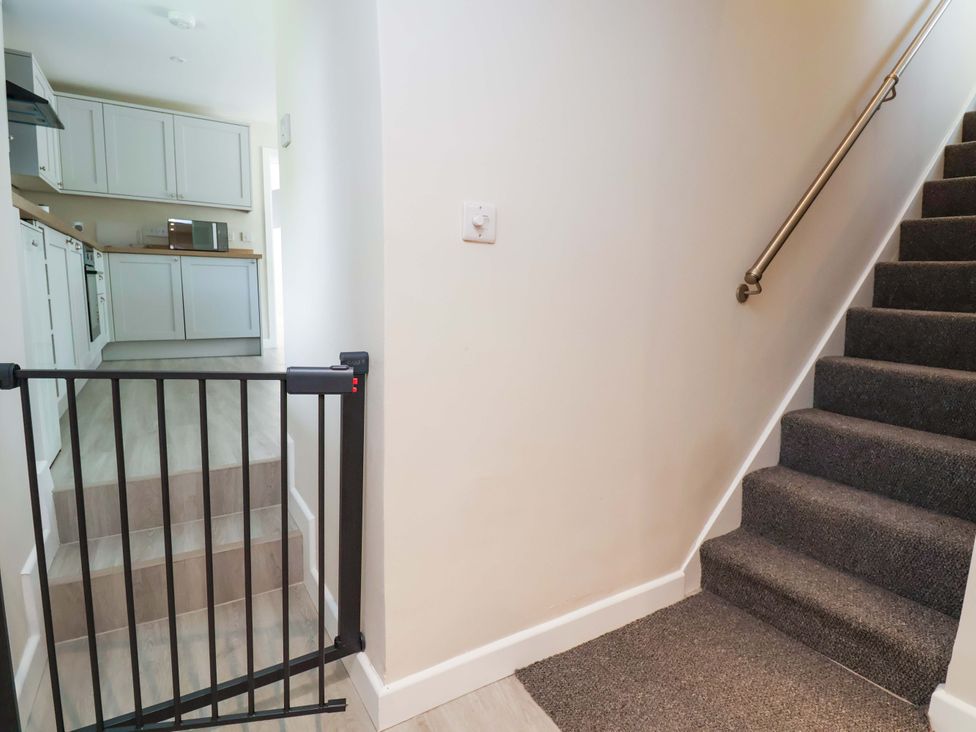 A hallway with a staircase and a kitchen at Cartref Pen Y Ball near Holywell