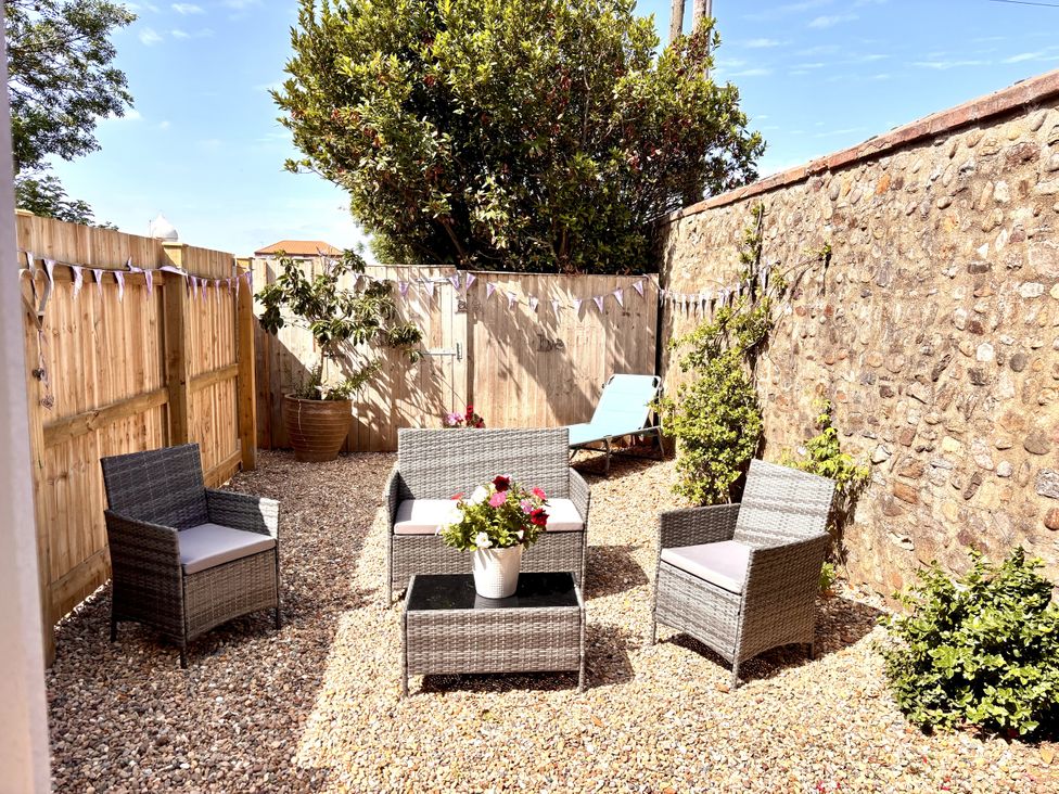 A garden with outdoor seating and a lounge chair at The Old Coach House at The Vicarage Mappleton near Hornsea