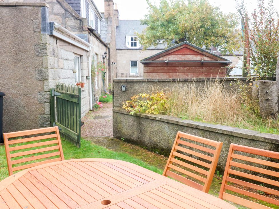 A garden with a wooden table and chairs at Evansford in Ballater