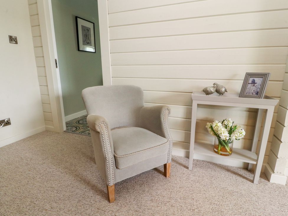 A snug with a chair and table at Manor Lodge in Clitheroe