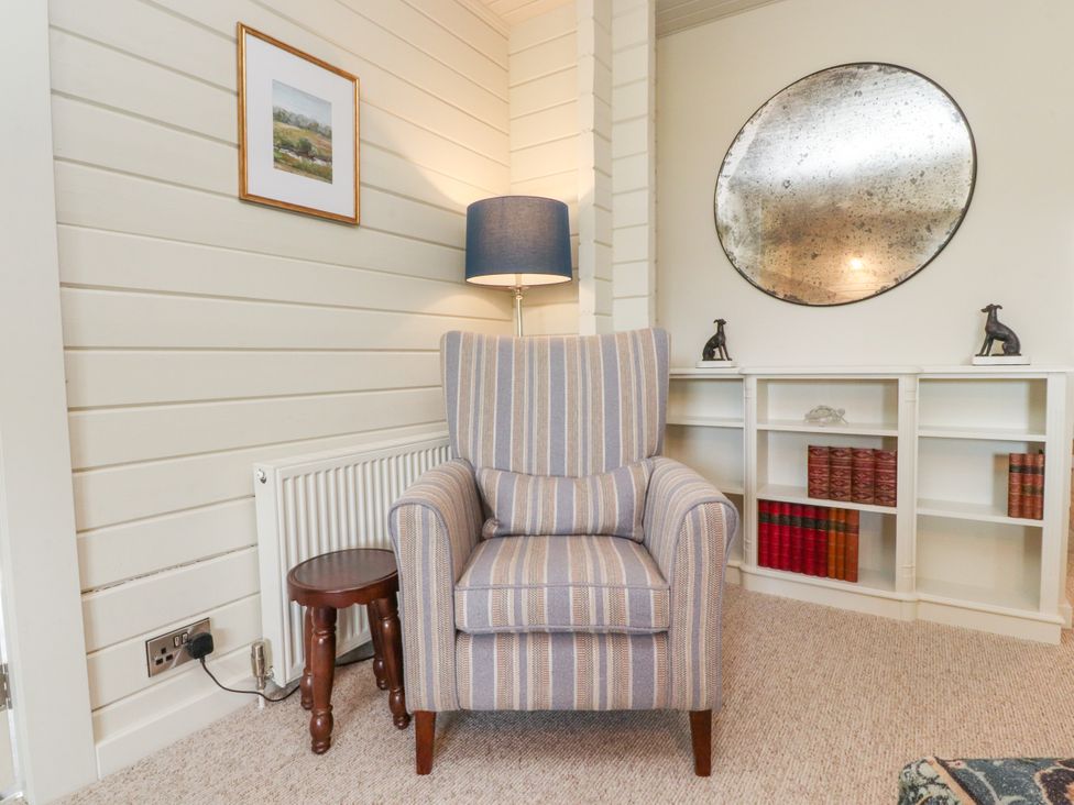 A snug with an armchair and lamp at Manor Lodge in Clitheroe