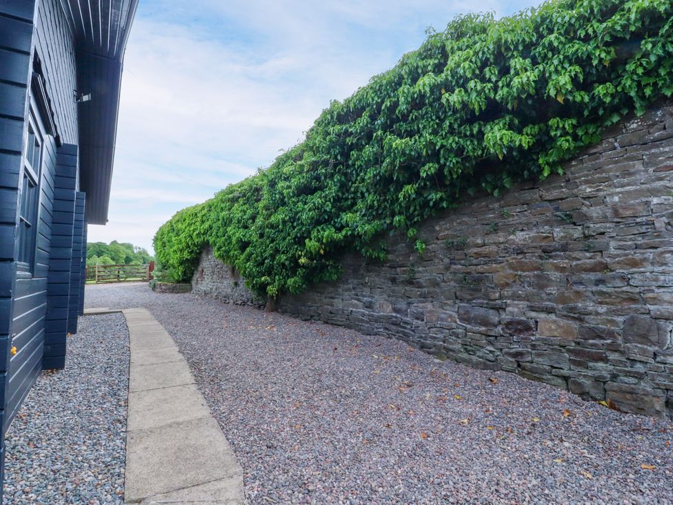 A gravel path beside a stone wall with a hedge at Manor Lodge in Clitheroe