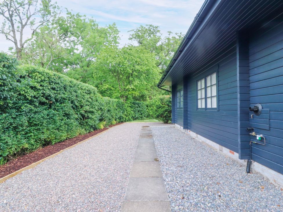 A pathway alongside a blue house with foliage at Manor Lodge in Clitheroe