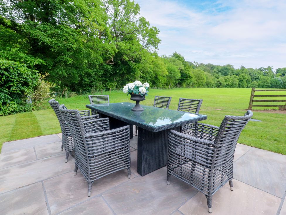 A dining table with chairs and flowers in an outdoor area at Manor Lodge in Clitheroe