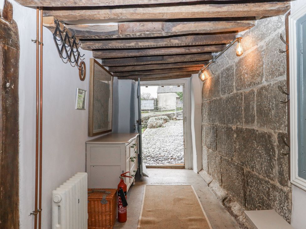 A hallway with stone walls and a door leading outside at Westacombe Farm in Dunsford