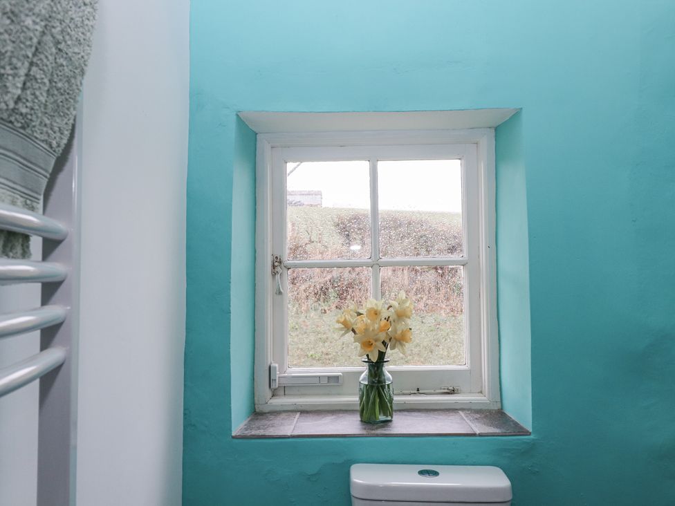 A bathroom with a window and flowers on the sill at Westacombe Farm in Dunsford