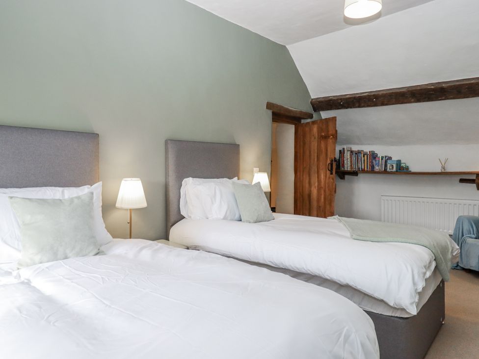 A bedroom with two beds and a shelf at Westacombe Farm in Dunsford