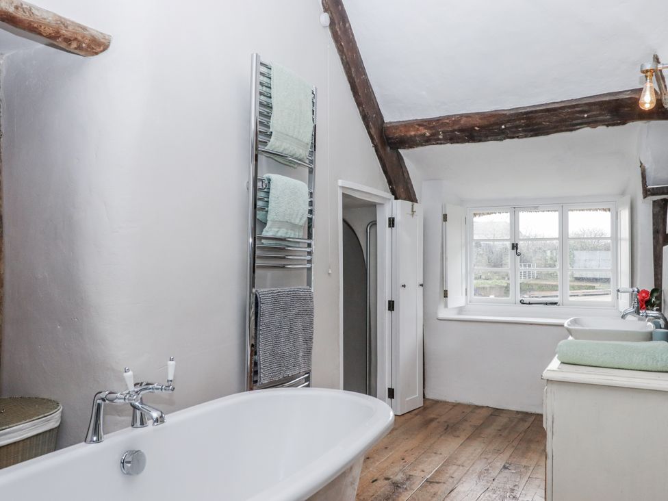 A bathroom with a bathtub, towel rack, and sink at Westacombe Farm in Dunsford