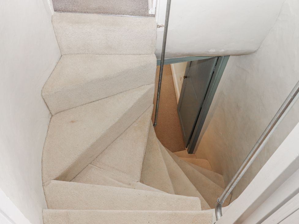 A staircase with a handrail leading to a door at Westacombe Farm in Dunsford